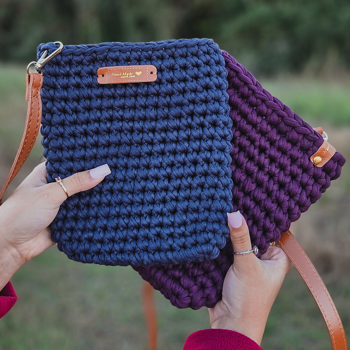 Two hands holding a blue and purple crocheted bag with a visible brand label.